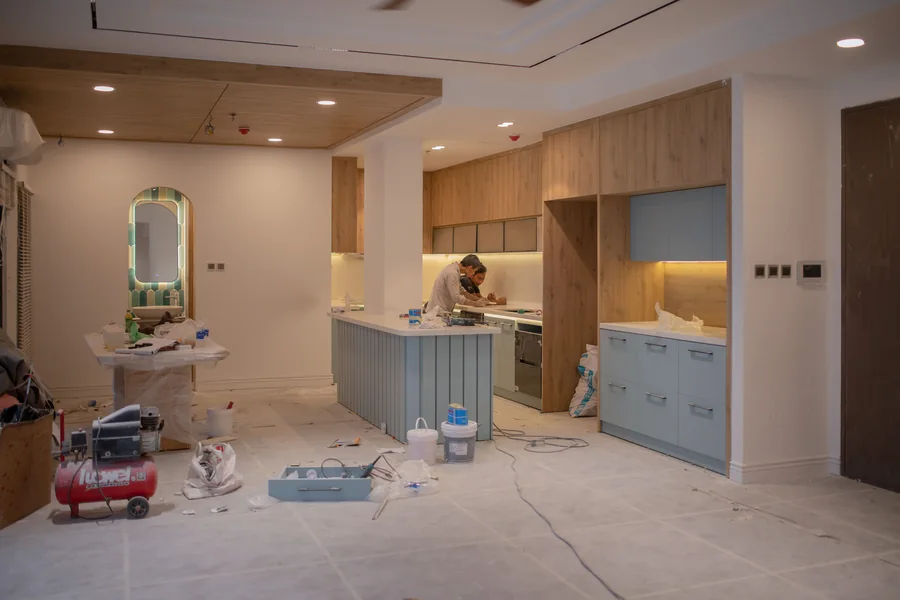 Cocina doméstica en remodelación con gabinetes, herramientas y materiales de obra.