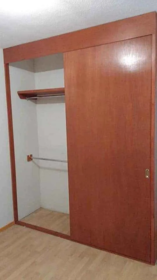 Closet en tono cerezo con puerta corrediza, entrepaño y tubo para colgar