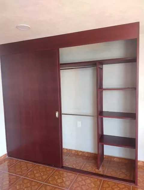 Closet en tono cerezo con puerta corrediza, entrepaños y tubo para colgar