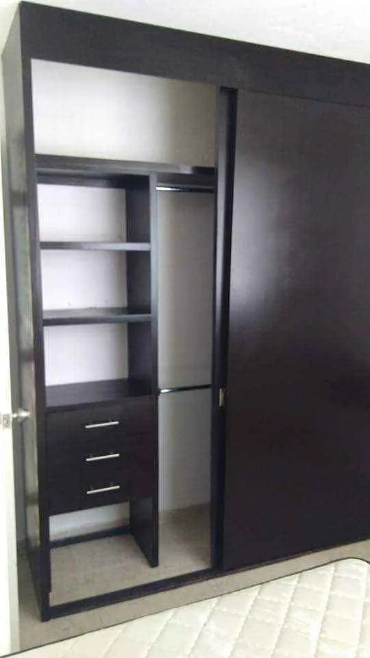 Closet en tono chocolate con puerta corrediza, entrepaños, cajones y tubo para colgar