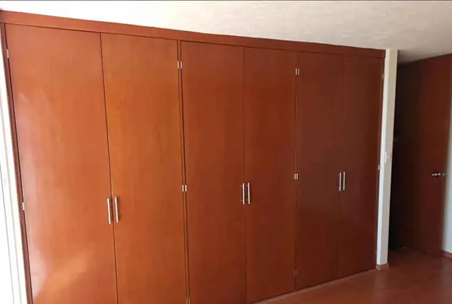 Closet de pared a pared en tono cerezo con seis puertas abatibles